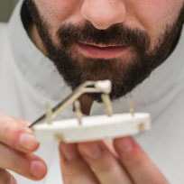 our dentist working on creating and shaping a dental crown for a patient